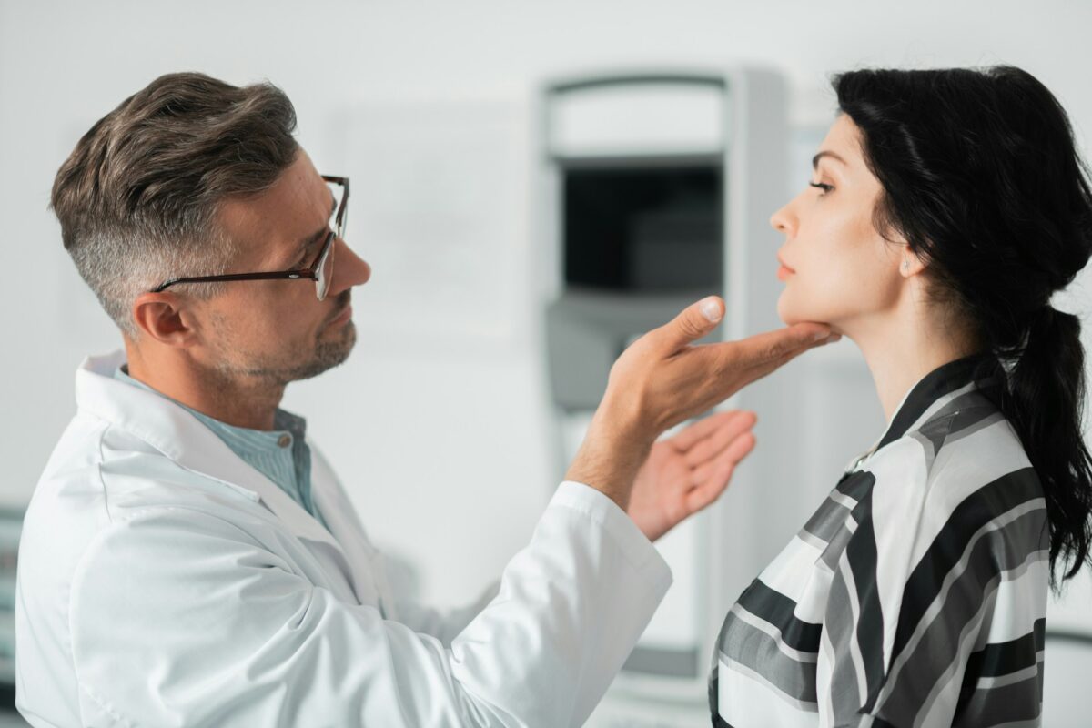 Board-certified plastic surgeon consulting with a patient during a facial evaluation before cosmetic surgery.