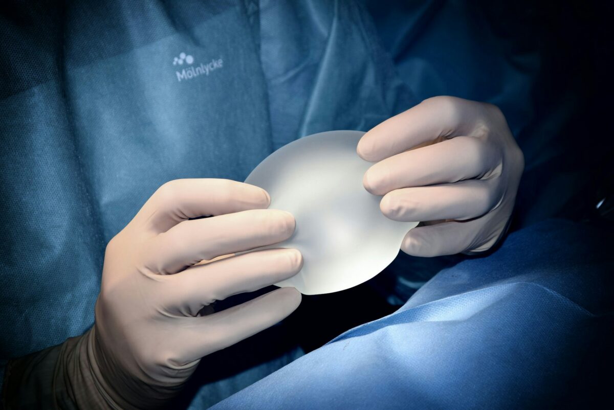 Breast surgeon holding a breast implant while preparing for breast augmentation surgery.