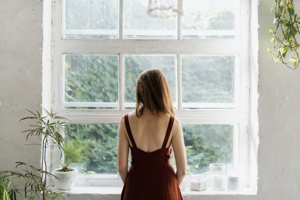 Patient looking out a window while planning plastic surgery recovery during changing Oklahoma weather.