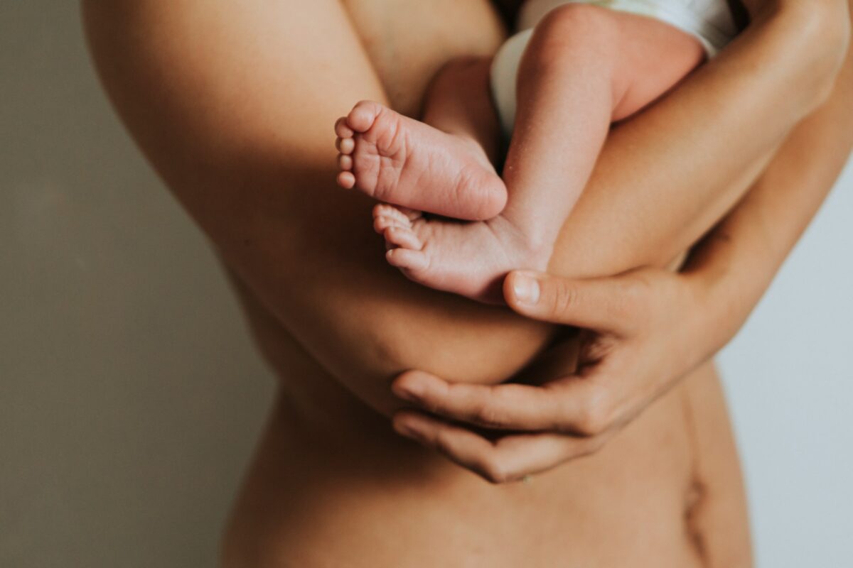 Mother holding her newborn, representing the physical changes after pregnancy that a tummy tuck can help address.
