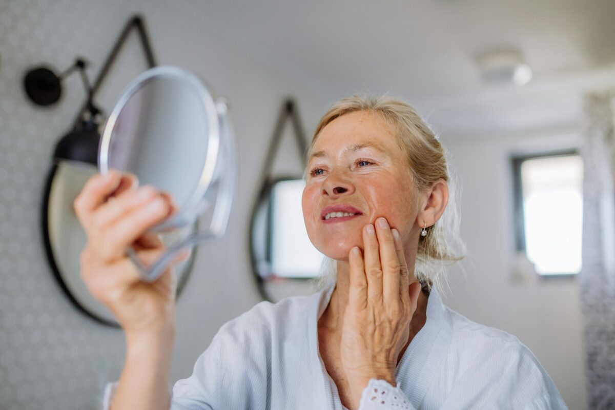 Woman admiring smoother, firmer skin after a PDO thread lift treatment for non-surgical facial rejuvenation.