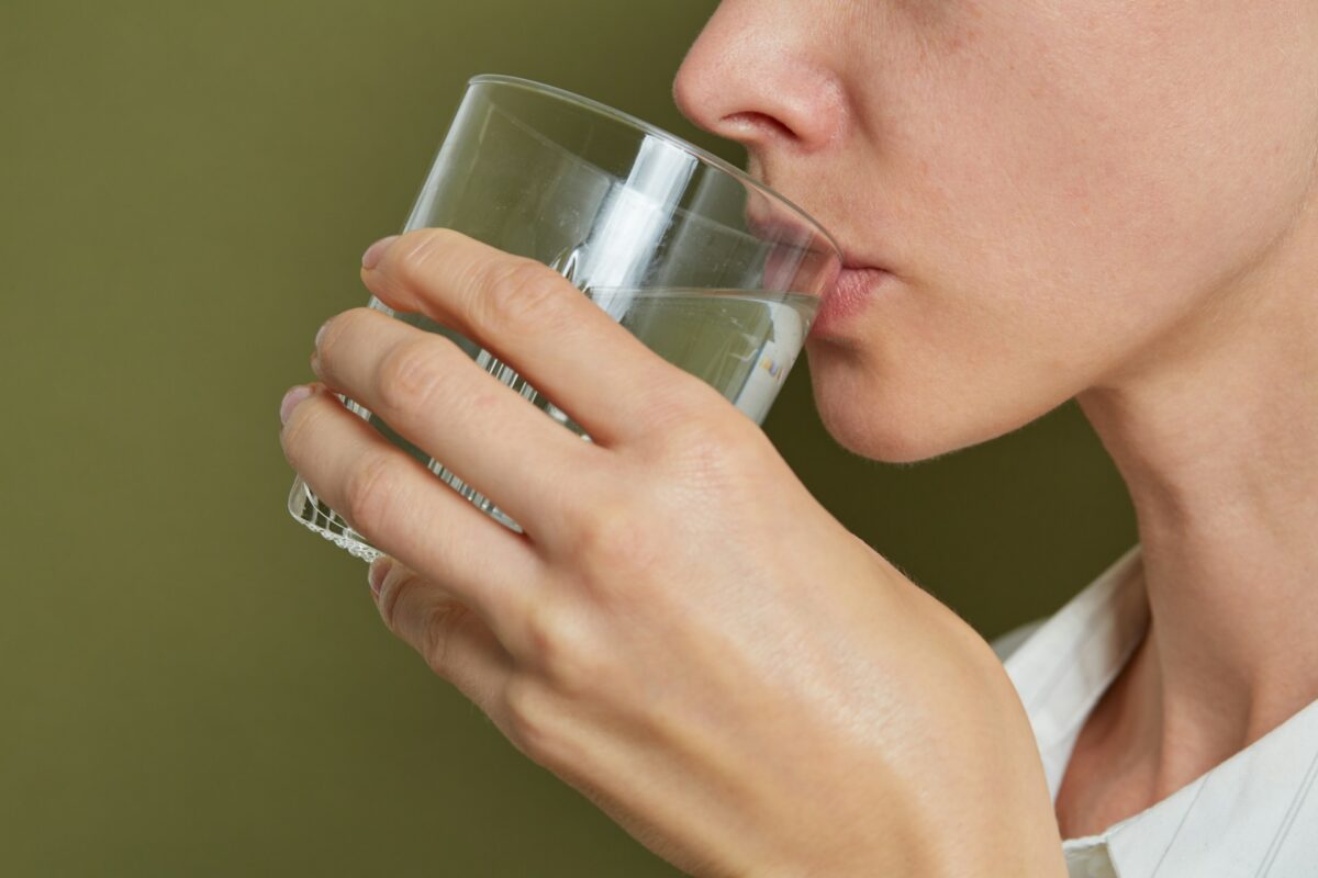 Patient staying hydrated during abdominoplasty recovery after tummy tuck surgery to support healing and recovery.