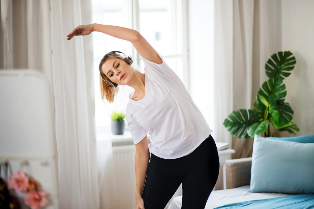 Woman exercising at home to reduce stubborn fat while considering body contouring treatments.