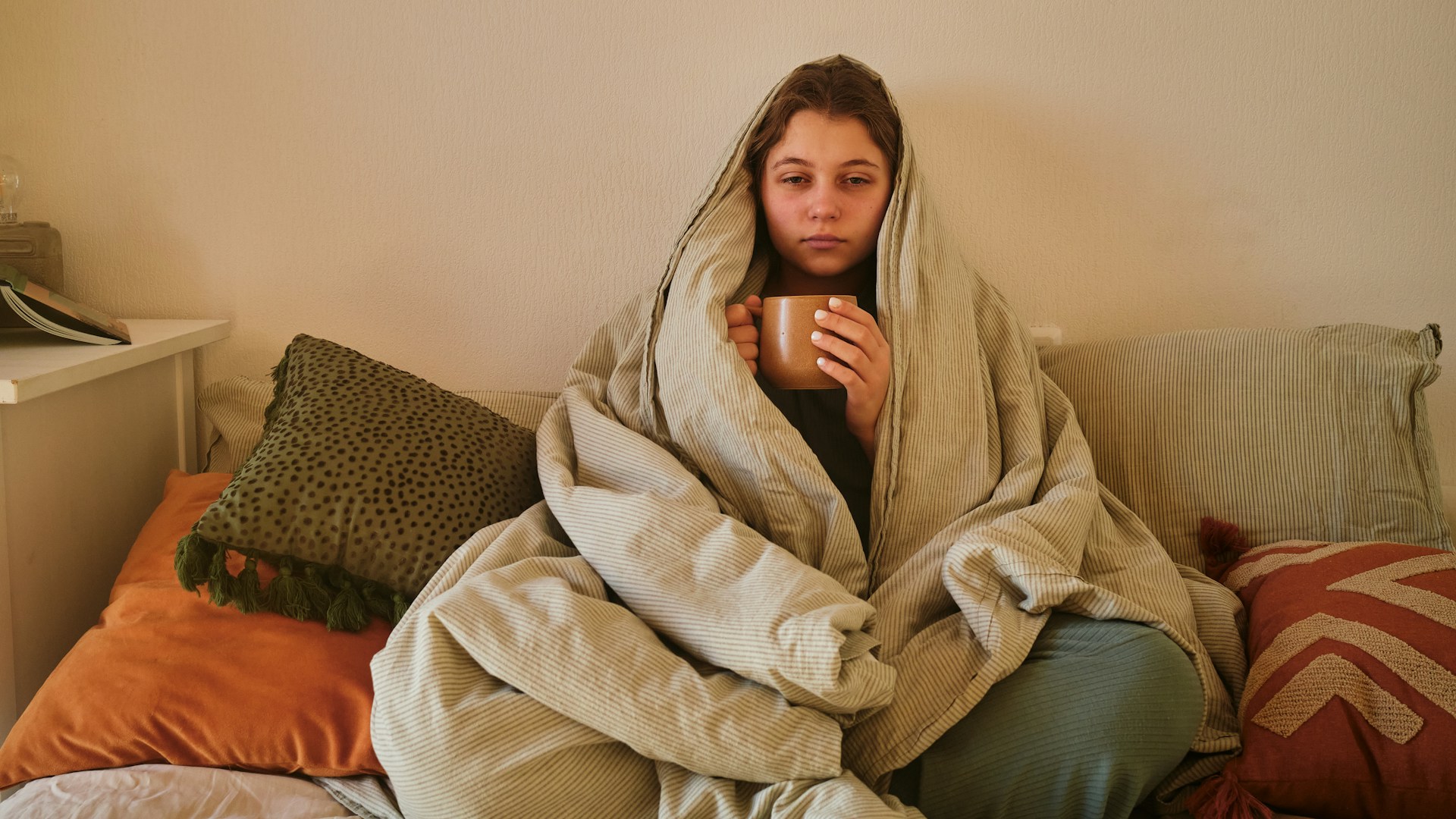 Woman wrapped in a blanket at home while recovering comfortably after plastic surgery in cold weather.
