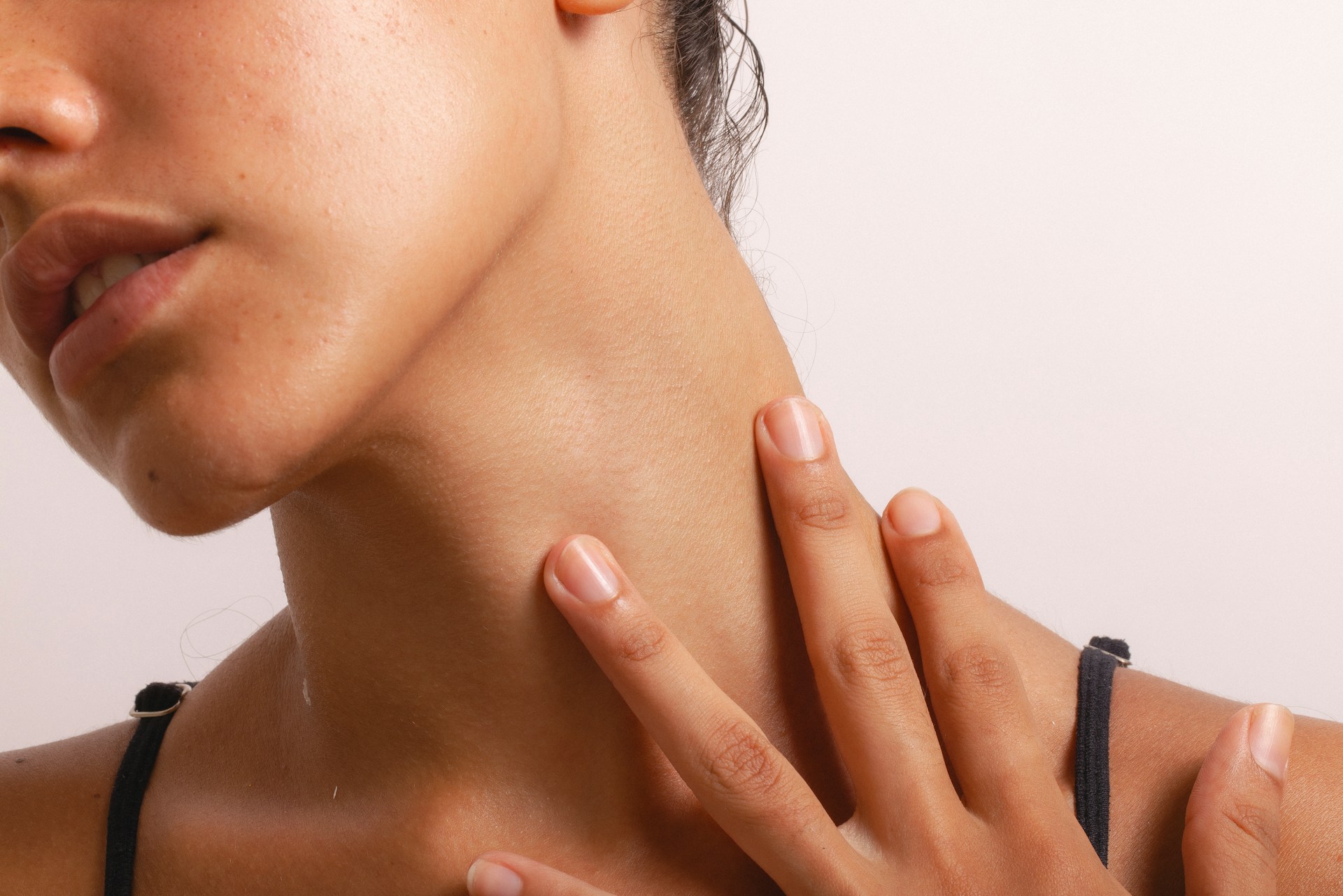 Woman touching her neck while considering Tixel for neck treatment to improve skin texture and firmness.
