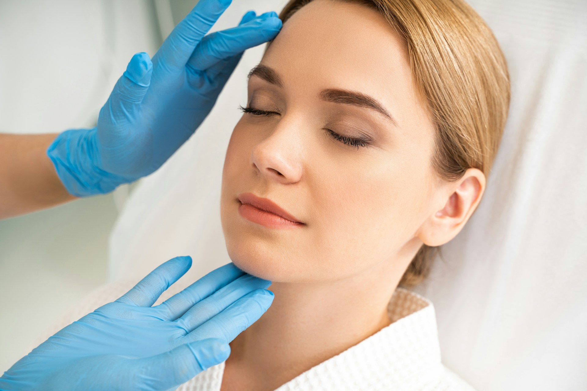 Woman receiving a facial assessment before Daxxify for wrinkles treatment in a clinical setting.