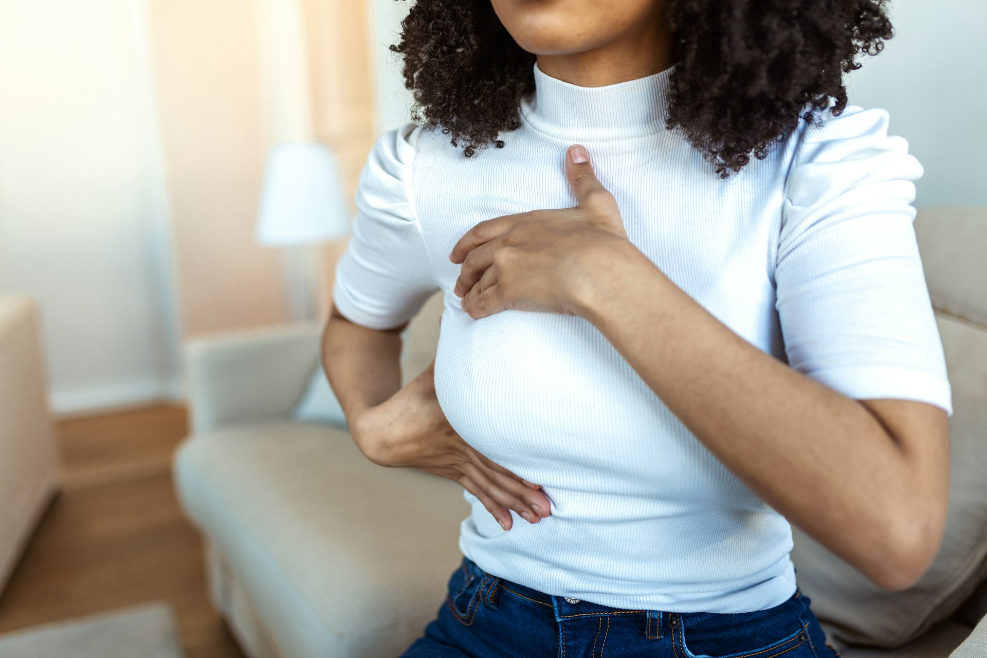 Woman holding her chest while considering breast reduction for improved comfort, posture, and relief from back strain.