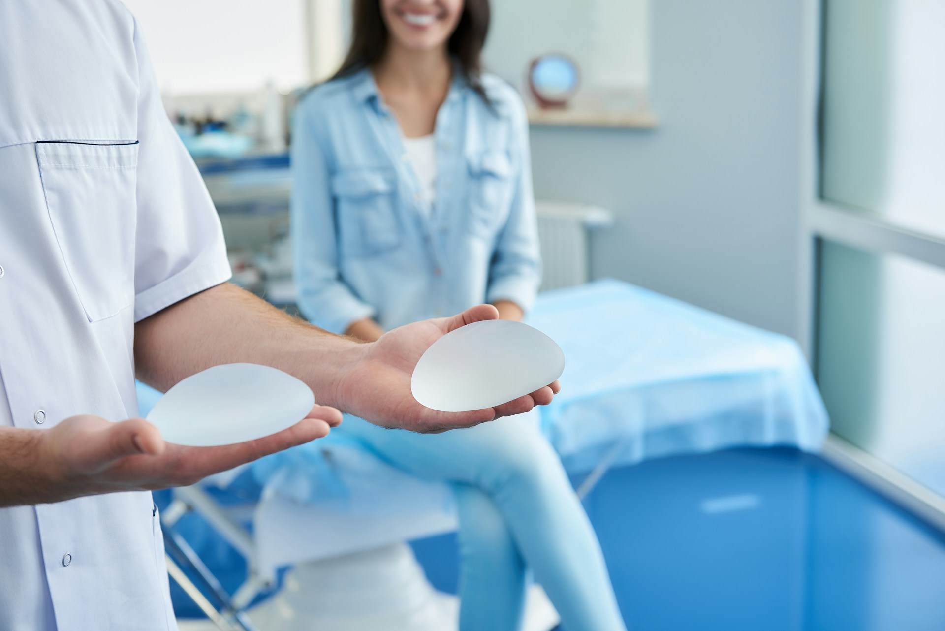 Surgeon holding breast implants during a consultation about breast implant removal options.