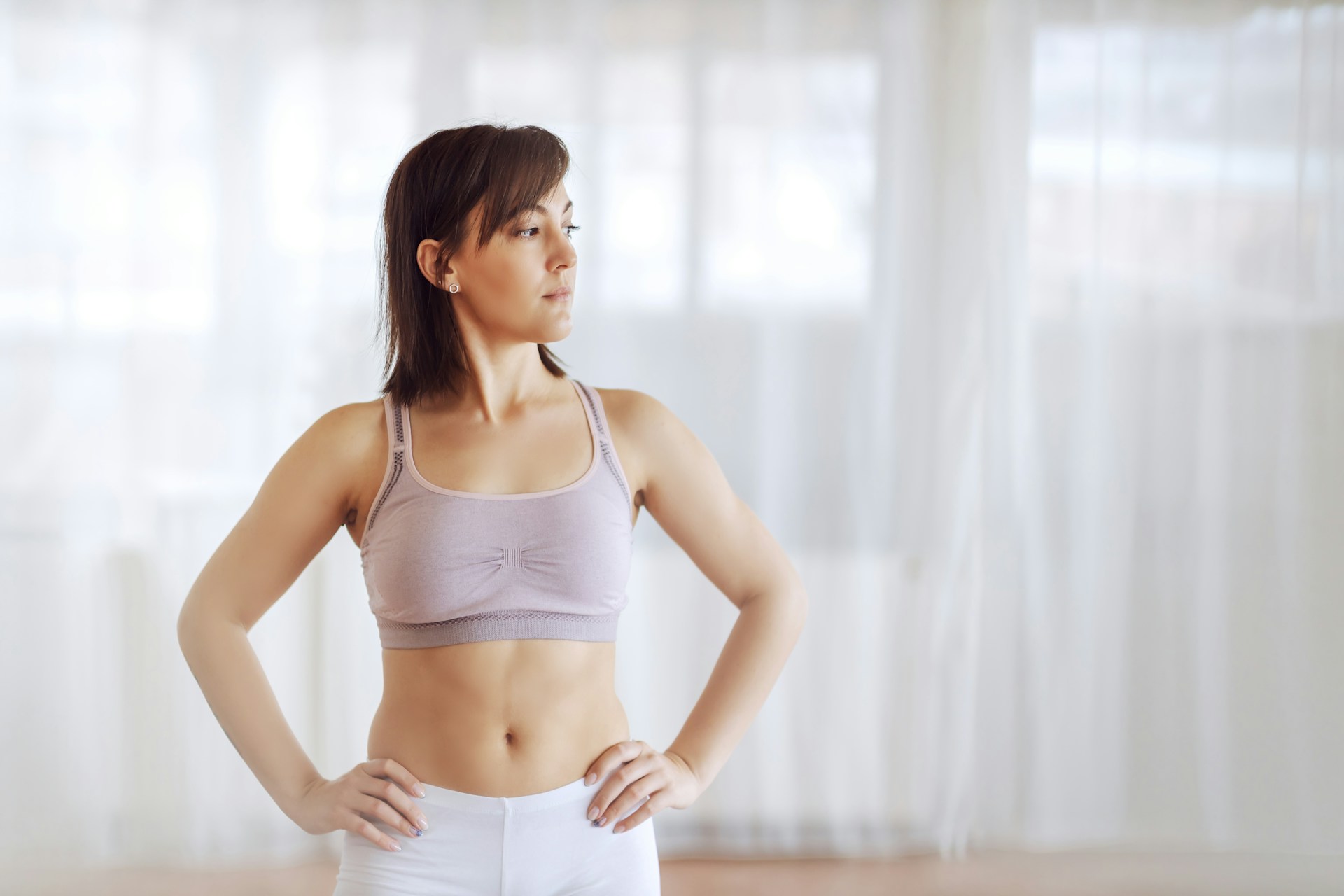Woman standing with hands on hips while considering tummy tuck recovery and body contouring results.