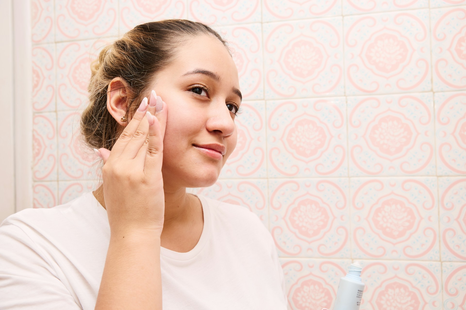 Woman applying skincare to her face while preparing her skin for PDO threads and thread lift recovery.