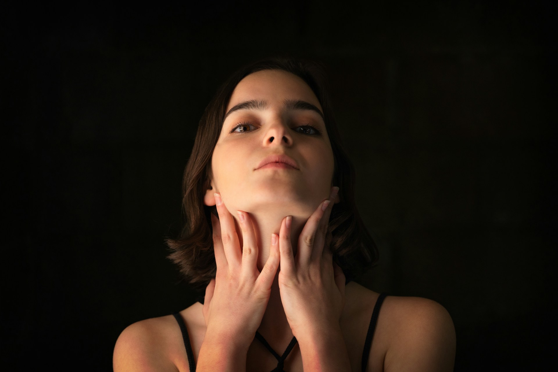 Woman touching her jawline and neck while considering PDO threads for subtle facial lifting and contour support.
